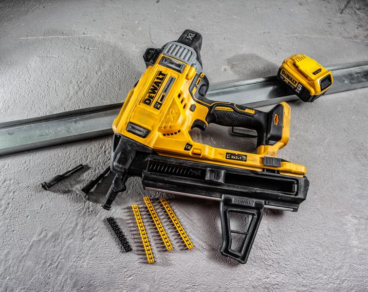 Uma pistola de pregos sem fio DEWALT com bateria, várias tiras de pregos e acessórios sobre uma superfície de concreto. A ferramenta é predominantemente amarela e preta e projetada para trabalhos de construção pesada.