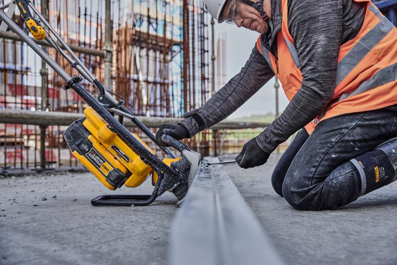 Uma pessoa com equipamento de segurança de construção usa uma ferramenta elétrica sem fio DEWALT (SKU: DCPS330N) em uma viga de metal em um canteiro de obras.